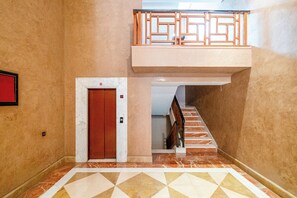 A hallway with a marble floor, a red door, and a staircase leading to a balcony. - Hyper Centre Plaza Balcony & Parking (Marrakech)