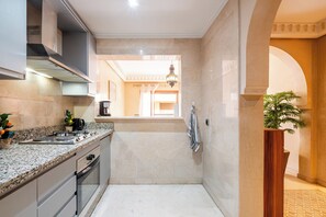 A modern kitchen with granite countertops, a built-in oven, and a stainless steel range hood. - Hyper Centre Plaza Balcony & Parking (Marrakech)
