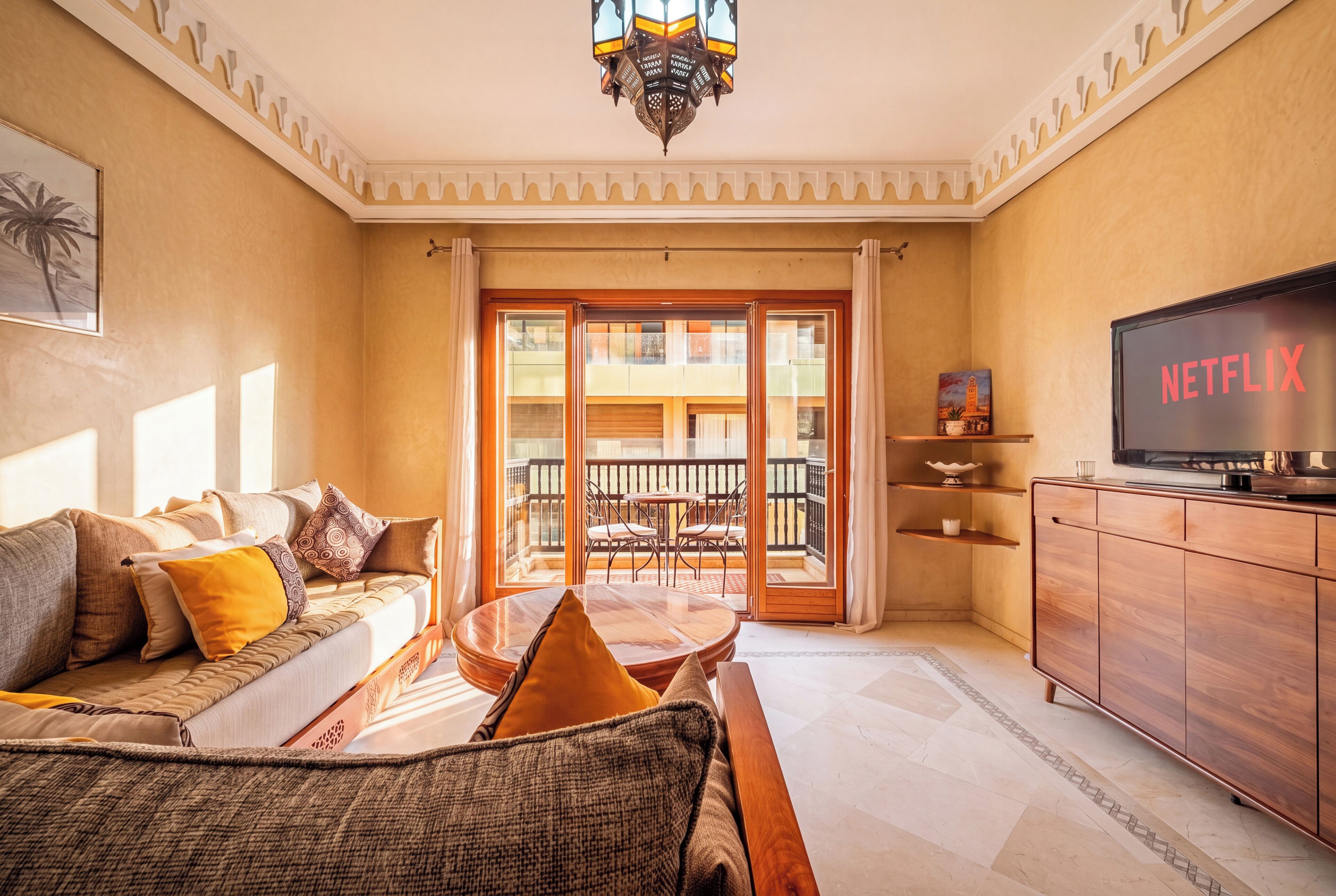 Ein Wohnzimmer mit einer Couch, einem Couchtisch, einem Fernseher und einem Balkon mit Blick.