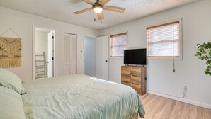 Ein Schlafzimmer mit einem Bett, einem Deckenventilator, einer Kommode und einem Fernseher.