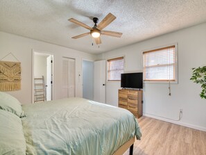 Ein Schlafzimmer mit einem Bett, einem Deckenventilator, einer Kommode und einem Fernseher.