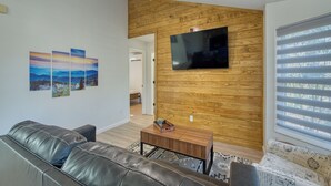 Ein Wohnzimmer mit einer Ledersofa, einem Holztisch und einem flachbildschirmfernseher an einer Holzwand.