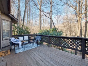 A wooden deck with a bench and a table, surrounded by a lattice railing. - Easy Access Cottage - Pet-Friendly -Maggie Valley. (Maggie Valley)