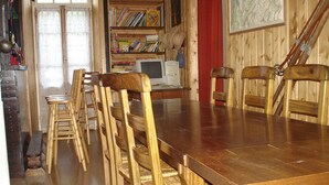 Ein Essbereich mit Holztisch und Stühlen, einem Bücherregal und einem Computer.