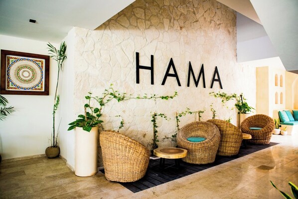 A lobby with a stone wall, wicker furniture, and potted plants.