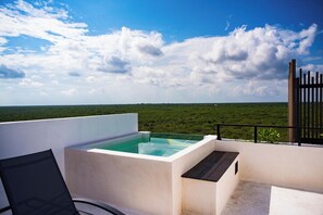 A rooftop terrace with a hot tub, a chair, and a view of a green landscape. - Private pool, Penthouse on Malecon, Gorgeous! (Mahahual)