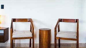 Dos sillas de madera con asientos y respaldos acolchados, un taburete de madera redondo y un equipo de aire acondicionado fijado a la pared.