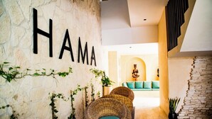 Una habitación con pared de piedra, un sofá de mimbre y un letrero en la pared que dice 'HAMA'.