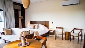 Habitación de hotel con cama, dos sillas, una mesa, lámpara y equipo de aire acondicionado.