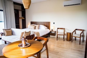 Habitación de hotel con cama, dos sillas, una mesa, lámpara y equipo de aire acondicionado.