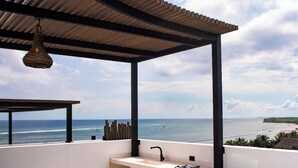 Un balcón con vista al mar, un lavabo y una silla.