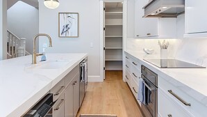 A modern kitchen with a marble countertop, stainless steel appliances, and a built-in oven. - Coastal Paradise- Brand new 4 bedroom with rooftop elevator (Holmes Beach)
