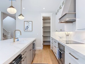 A modern kitchen with a marble countertop, stainless steel appliances, and a built-in oven. - Coastal Paradise- Brand new 4 bedroom with rooftop elevator (Holmes Beach)