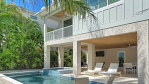 A pool area with lounge chairs and a covered seating area. - Coastal Paradise- Brand new 4 bedroom with rooftop elevator (Holmes Beach)