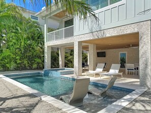 A pool area with lounge chairs and a covered seating area. - Coastal Paradise- Brand new 4 bedroom with rooftop elevator (Holmes Beach)