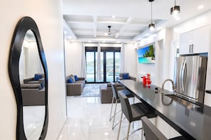 A modern kitchen with a large island, stainless steel appliances, and a view to the outside.