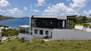 Ein modernes, zweistöckiges Haus mit Balkon, Pool und Meerblick.