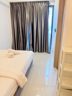 Ett hotellrum med en säng, ett badrum med en vit hylla och utsikt genom en dörr.