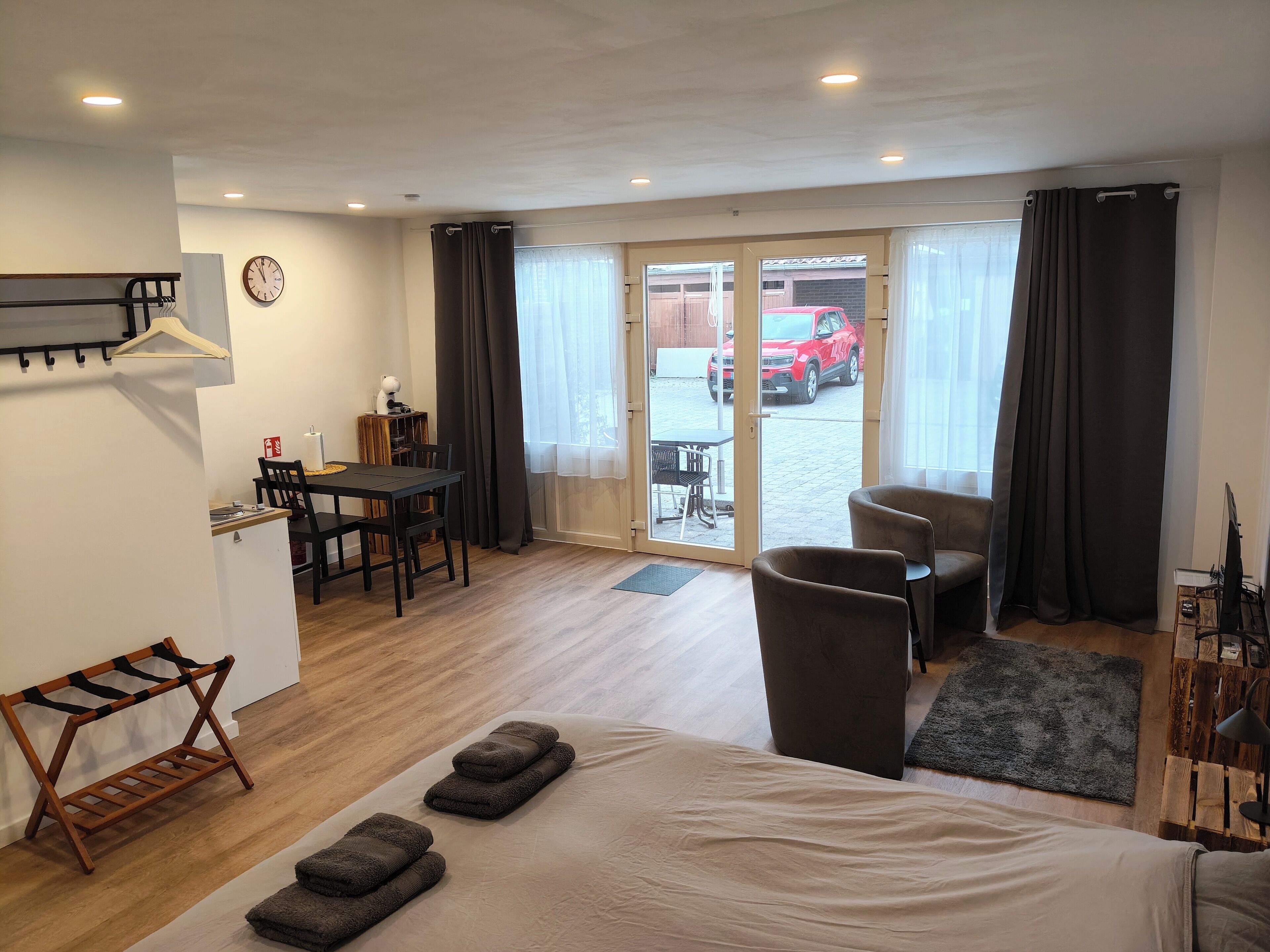 Une chambre d’hôtel avec un lit, un bureau, une chaise et une vue sur une voiture rouge garée à l’extérieur.