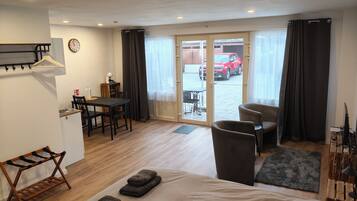 Une chambre d’hôtel avec un lit, un bureau, une chaise et une vue sur une voiture rouge garée à l’extérieur.