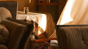 Um quarto com uma mesa, cadeiras, um armário e uma luminária.
