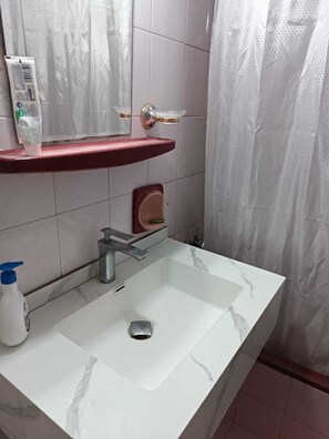 A bathroom with a white marble sink, a mirror, a red shelf, and a shower curtain. - Cozy 1-bedroom apartment in adorable Amman with AC (Amman)