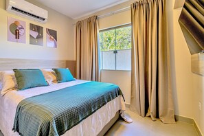 Une chambre d’hôtel avec un lit, une fenêtre avec des rideaux et des œuvres d’art murales.