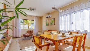 Un coin repas avec une table et des chaises en bois, un canapé et une grande fenêtre avec des rideaux.