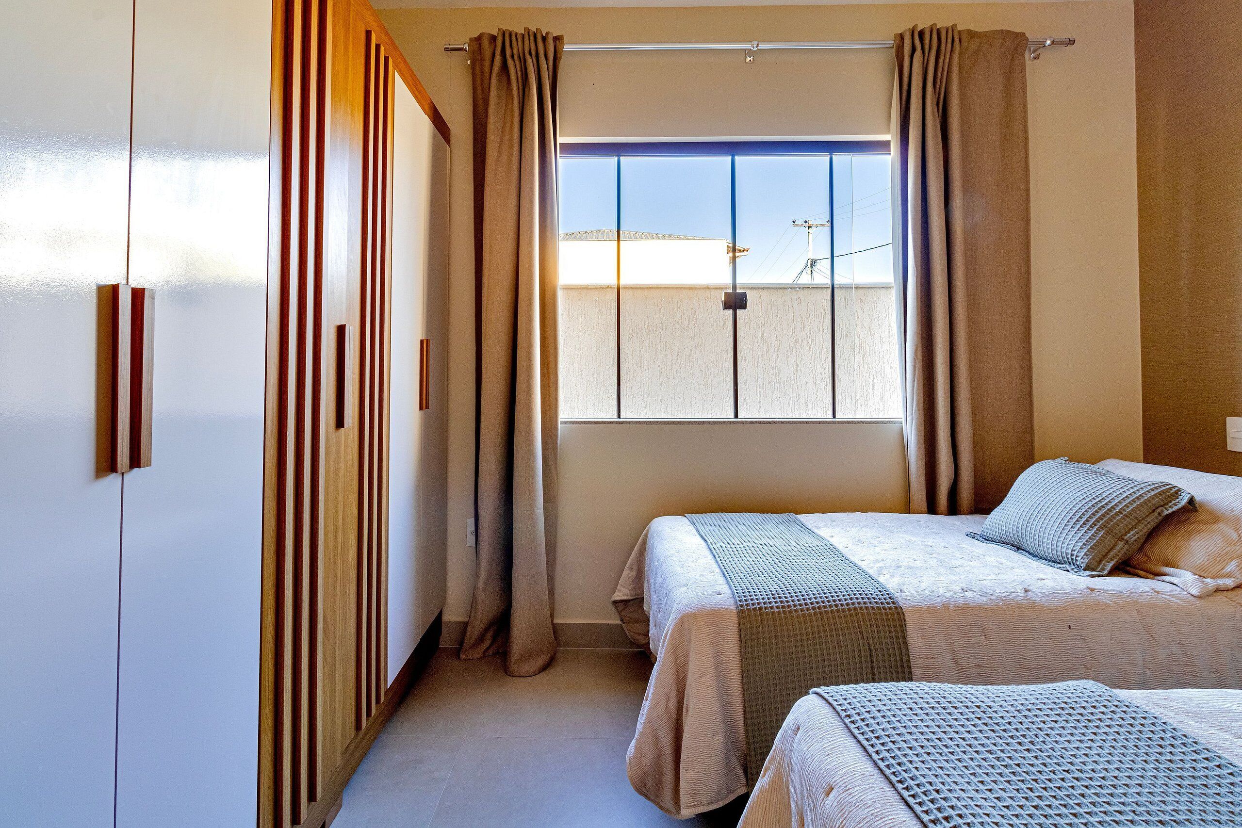 Un dormitorio con dos camas, una ventana con cortinas y vistas al exterior.