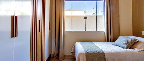 Un dormitorio con dos camas, una ventana con cortinas y vistas al exterior.