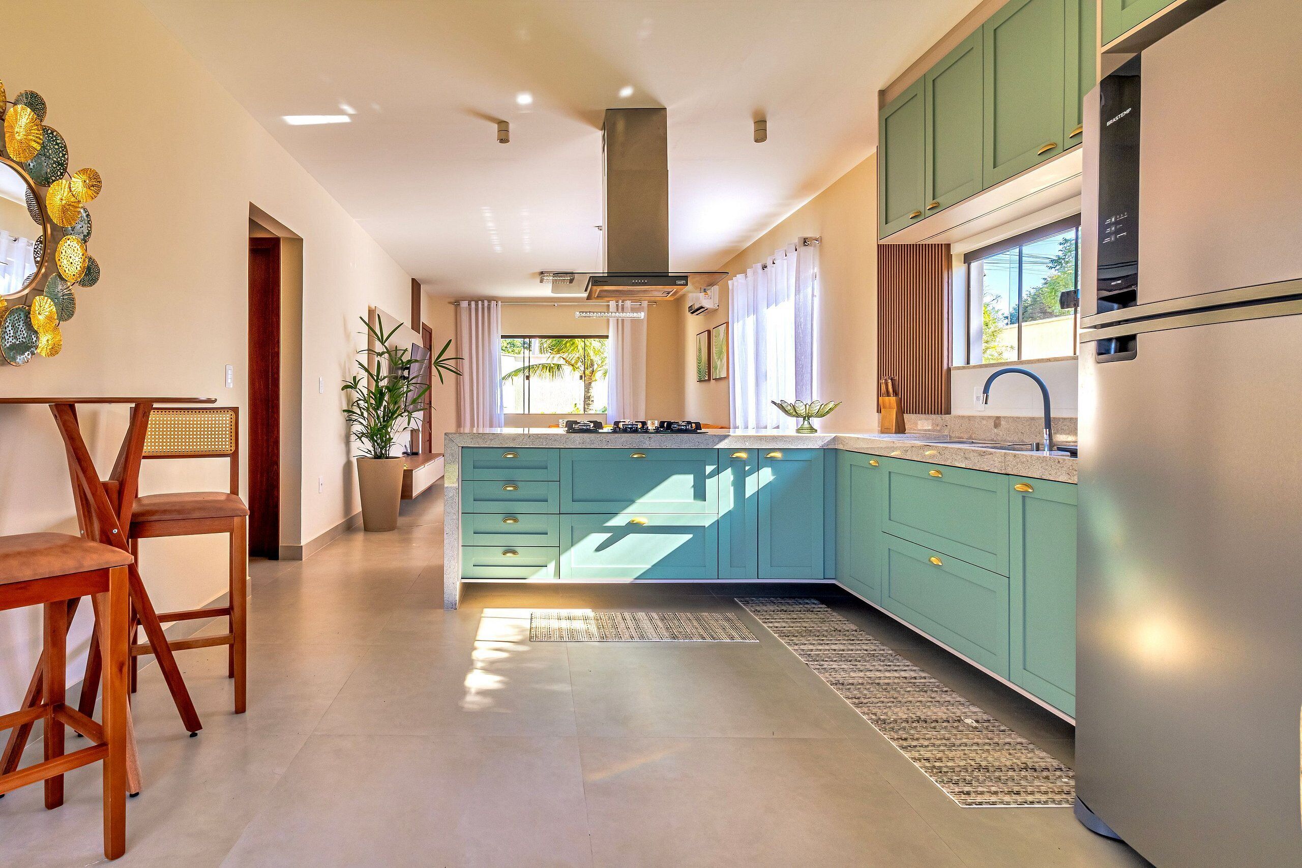 A modern kitchen with teal cabinetry, a built-in stove, and a stainless steel refrigerator.