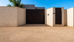 Une entrée fermée par un portail en métal et un panneau indiquant le numéro de l’adresse.
