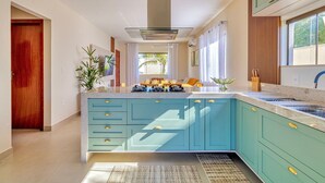 Une cuisine moderne dotée d’un îlot central, d’une cuisinière intégrée et d’une fenêtre avec des rideaux.