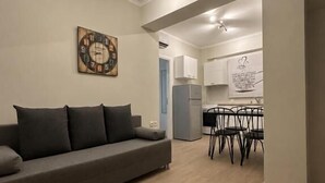 Una sala de estar con un sofá, un reloj y un comedor con sillas y una mesa.