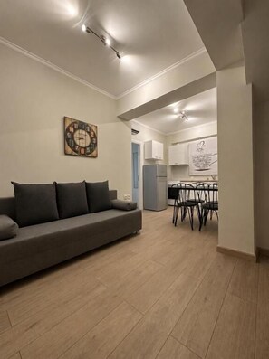 Una sala de estar con un sofá, un reloj y un comedor con sillas y una mesa.