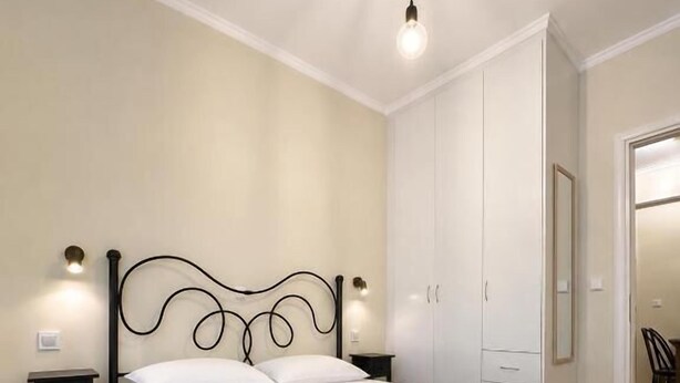 Un dormitorio con cama, mesitas de noche y un armario.