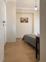 Un dormitorio con cama, una mesita de noche con toallas, una obra de arte en la pared y una lámpara colgante.
