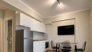 Una cocina moderna con armarios blancos, un refrigerador empotrado y una zona de comedor con mesa y sillas.