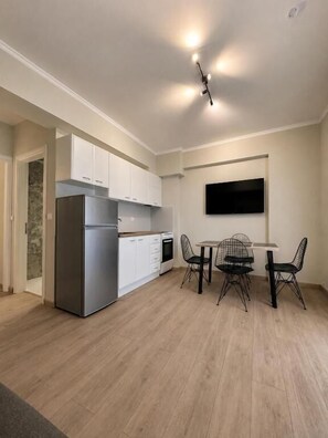 Una cocina moderna con armarios blancos, un refrigerador empotrado y una zona de comedor con mesa y sillas.