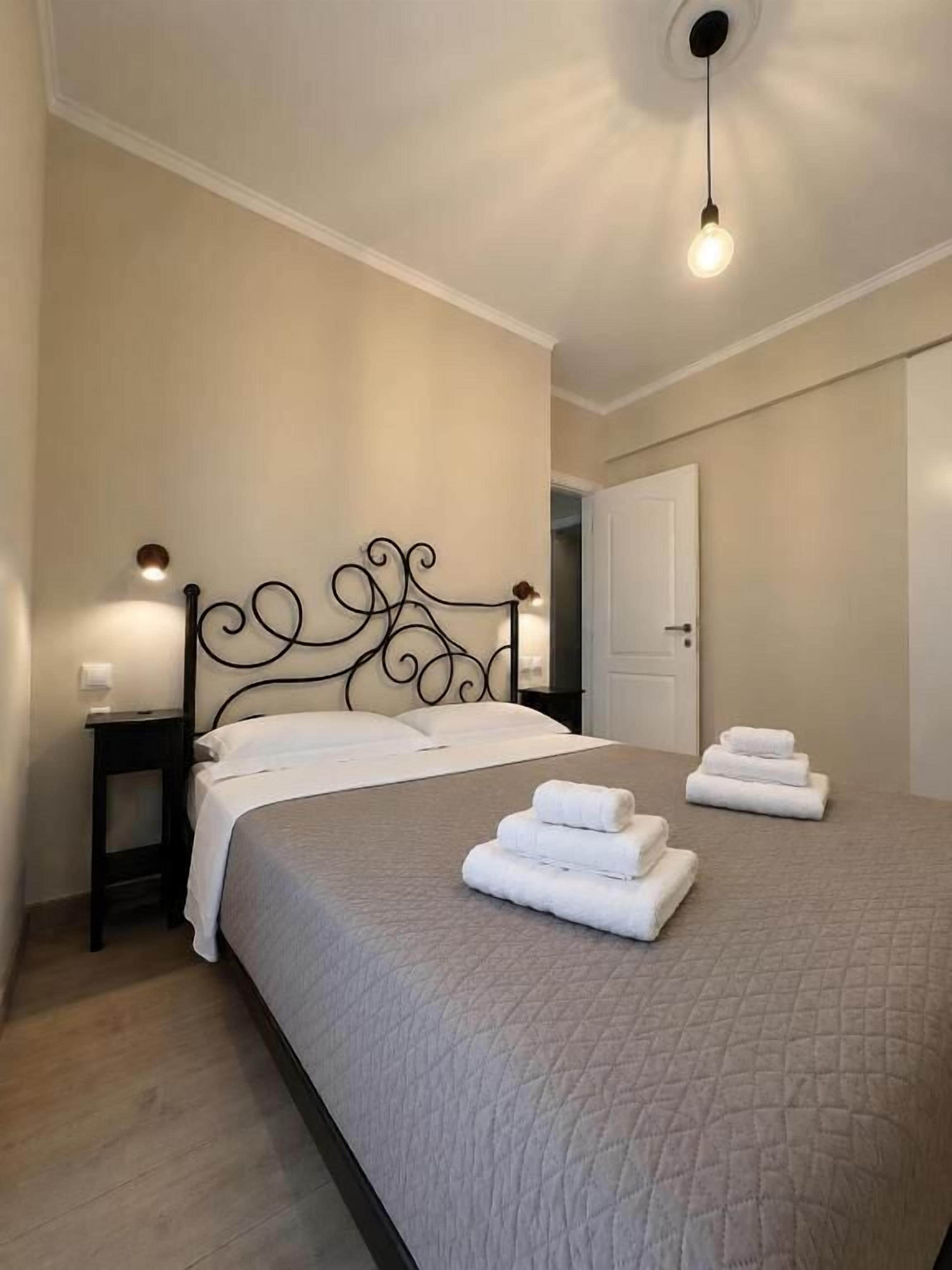 Een slaapkamer met een bed, twee nachtkastjes, een deur en een hanglamp.