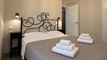 Een slaapkamer met een bed, twee nachtkastjes, een deur en een hanglamp.