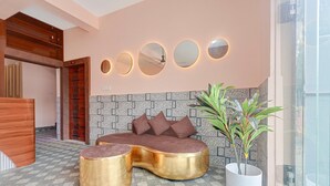 A modern lobby with a sofa, two gold side tables, a potted plant, and a wall with circular mirrors. - Classic Bhubaneswar New Station Road (Bhubaneshwar)