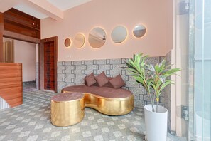 A modern lobby with a sofa, two gold side tables, a potted plant, and a wall with circular mirrors. - Classic Bhubaneswar New Station Road (Bhubaneshwar)