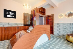 A hotel room with a wooden vanity, a mirror, a sign indicating the hotel name, and a tiled floor.