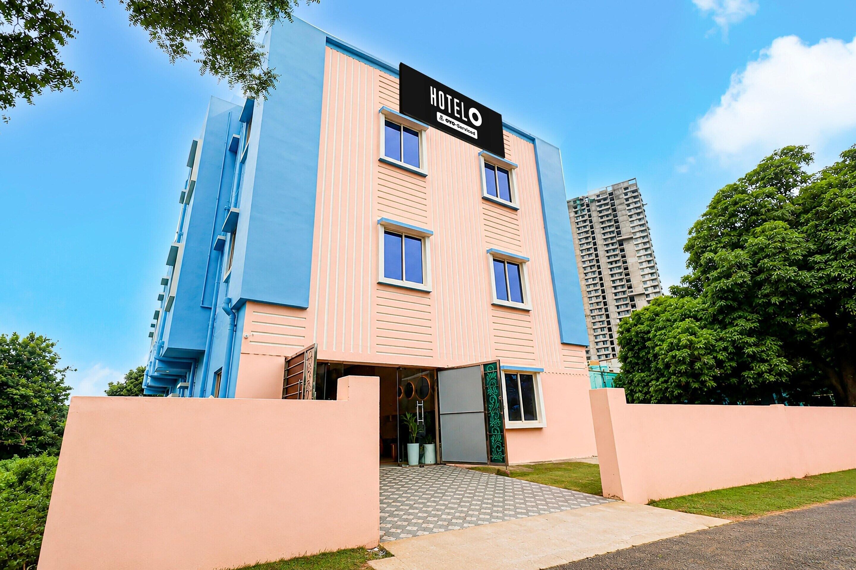 A multi-story hotel with a prominent sign, a gated entrance, and a parking area.