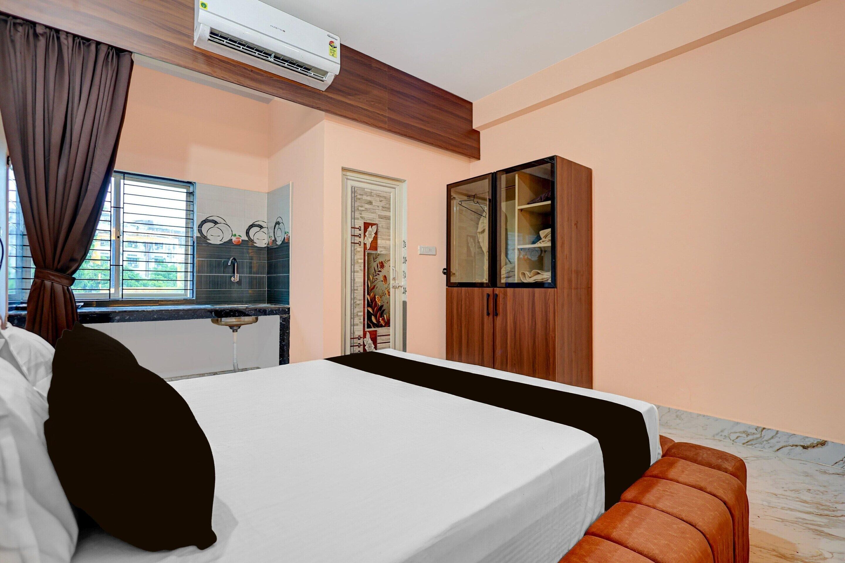 Un dormitorio con cama, aire acondicionado, armario y ventana con cortinas.