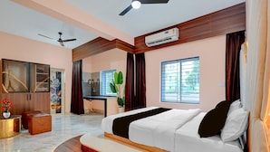 Une chambre moderne avec un grand lit, un ventilateur de plafond, un appareil de climatisation, un bureau et une fenêtre donnant sur un beau paysage.