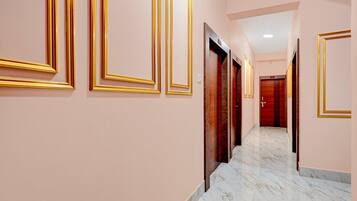 A corridor with marble flooring and doors with golden frames.