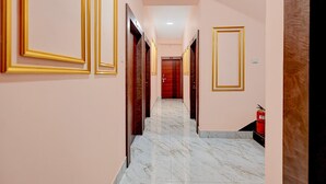 A hotel hallway with marble flooring, golden door frames, and a fire extinguisher on the right. - Classic Bhubaneswar New Station Road (Bhubaneshwar)