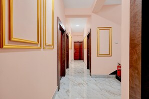 A hotel hallway with marble flooring, golden door frames, and a fire extinguisher on the right. - Classic Bhubaneswar New Station Road (Bhubaneshwar)
